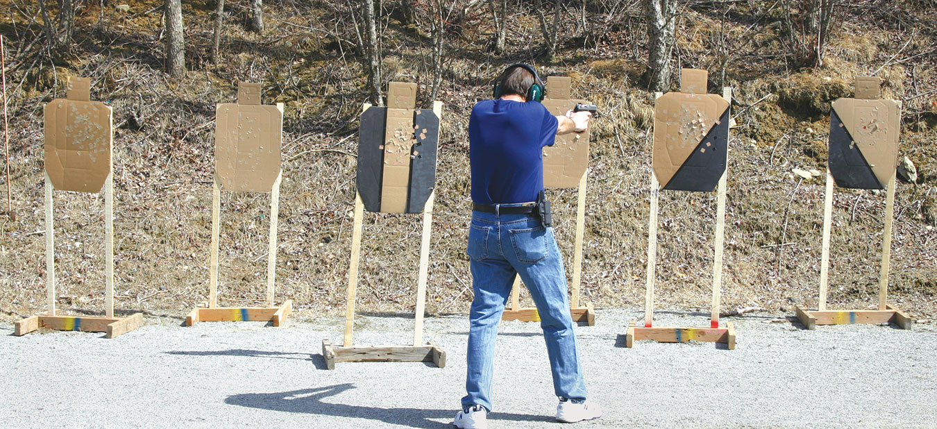 multiple cardboard silhouette targets being engaged by a shooter with a pistol for street training