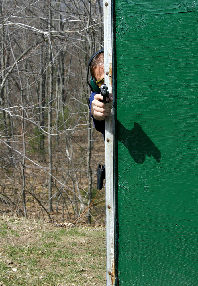 Man shooting a pistol with only his hand and half of his head exposed, as you would after street training