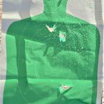 green silhouette target peppered with bird shot
